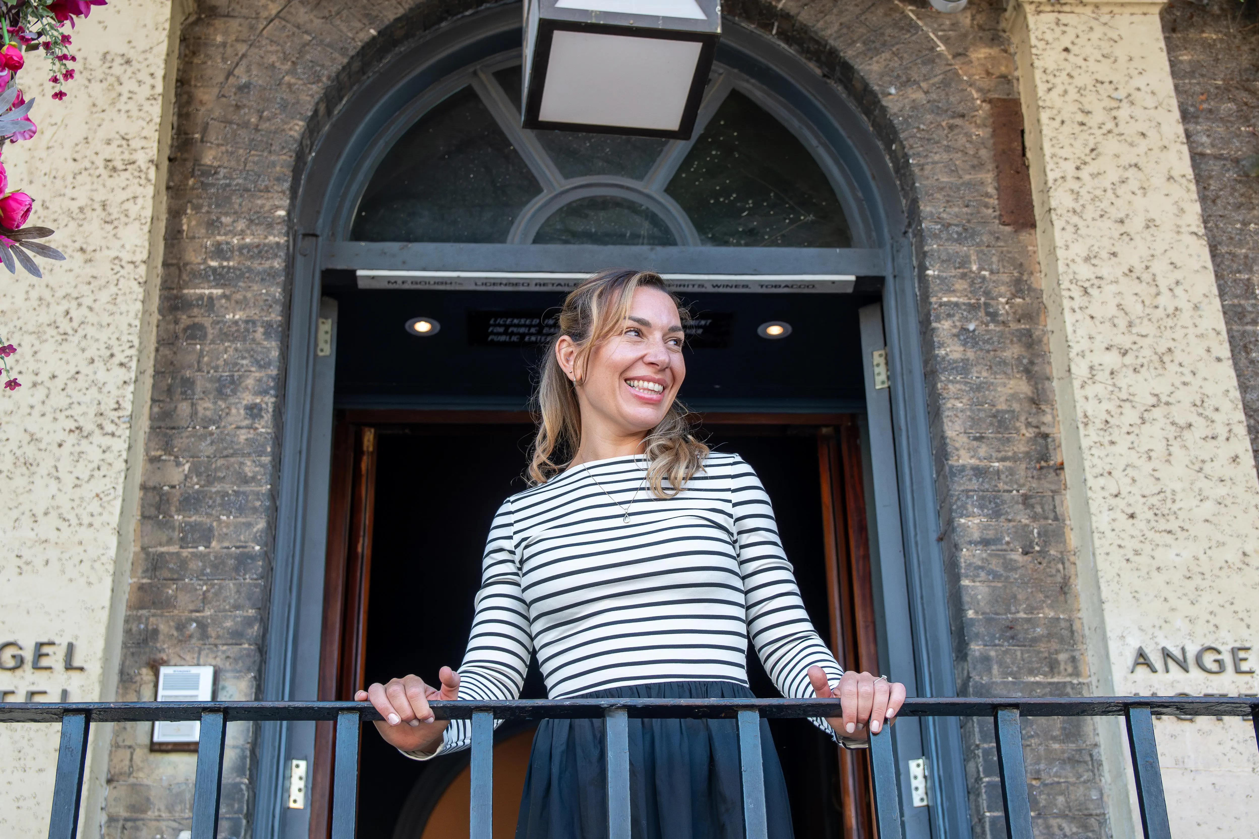 RI Coaching - Woman with arms outstretched in joyful pose on balcony